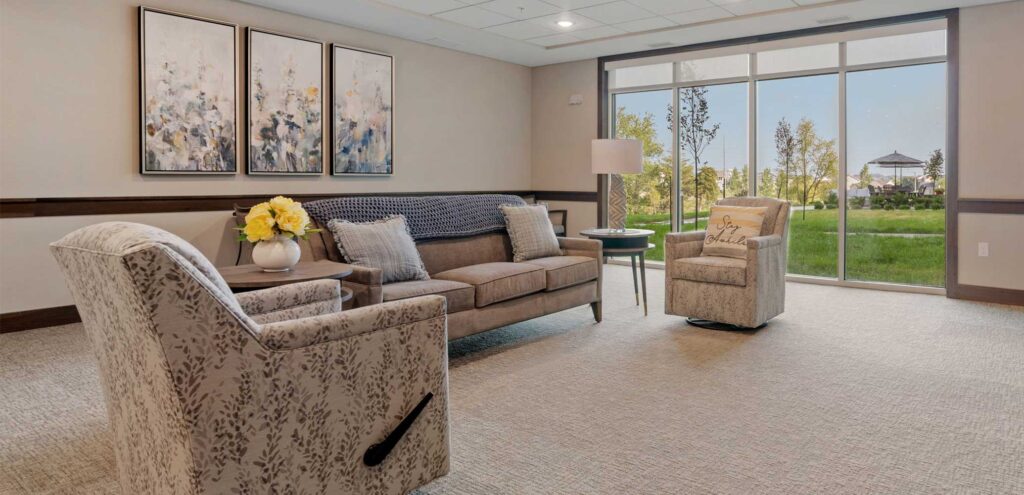 Bright shared lounge space with comfortable seating in memory care at Meadowview of Clive.